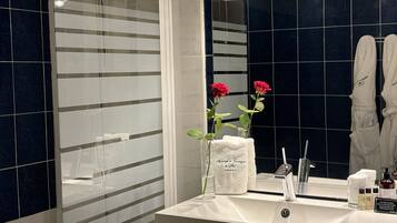 Une salle de bain moderne avec un grand miroir, un lavabo blanc et une cabine de douche en verre.