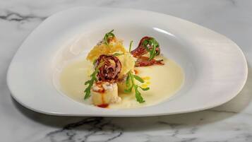 Une assiette blanche contenant un plat, agrémenté de verdure et d’une sauce.