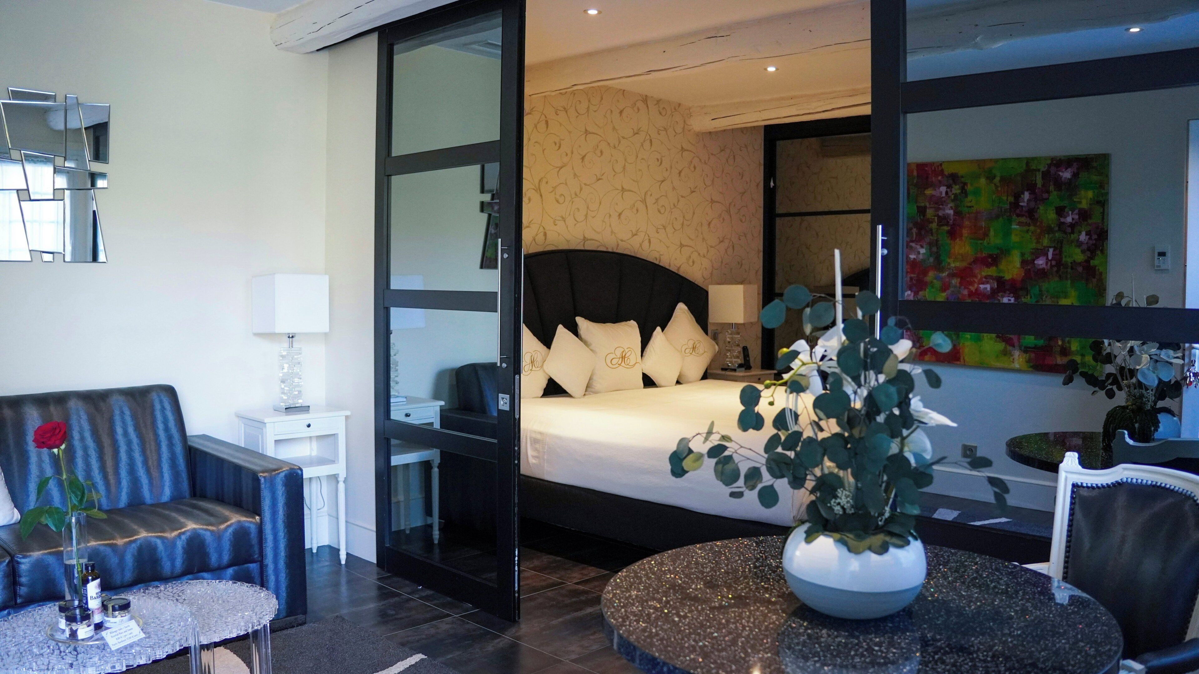Una habitació d'hotel moderna amb un llit, una zona de seients amb un sofà i una taula, i una finestra gran.