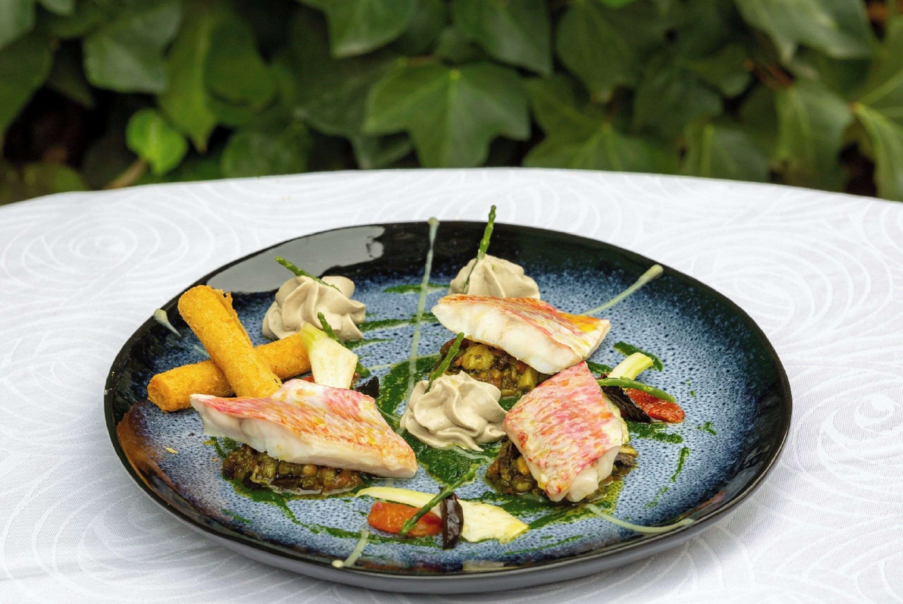 Une assiette remplie de différents mets, notamment des raviolis, des légumes et, éventuellement, des fruits de mer, le tout présenté sur une assiette décorative.