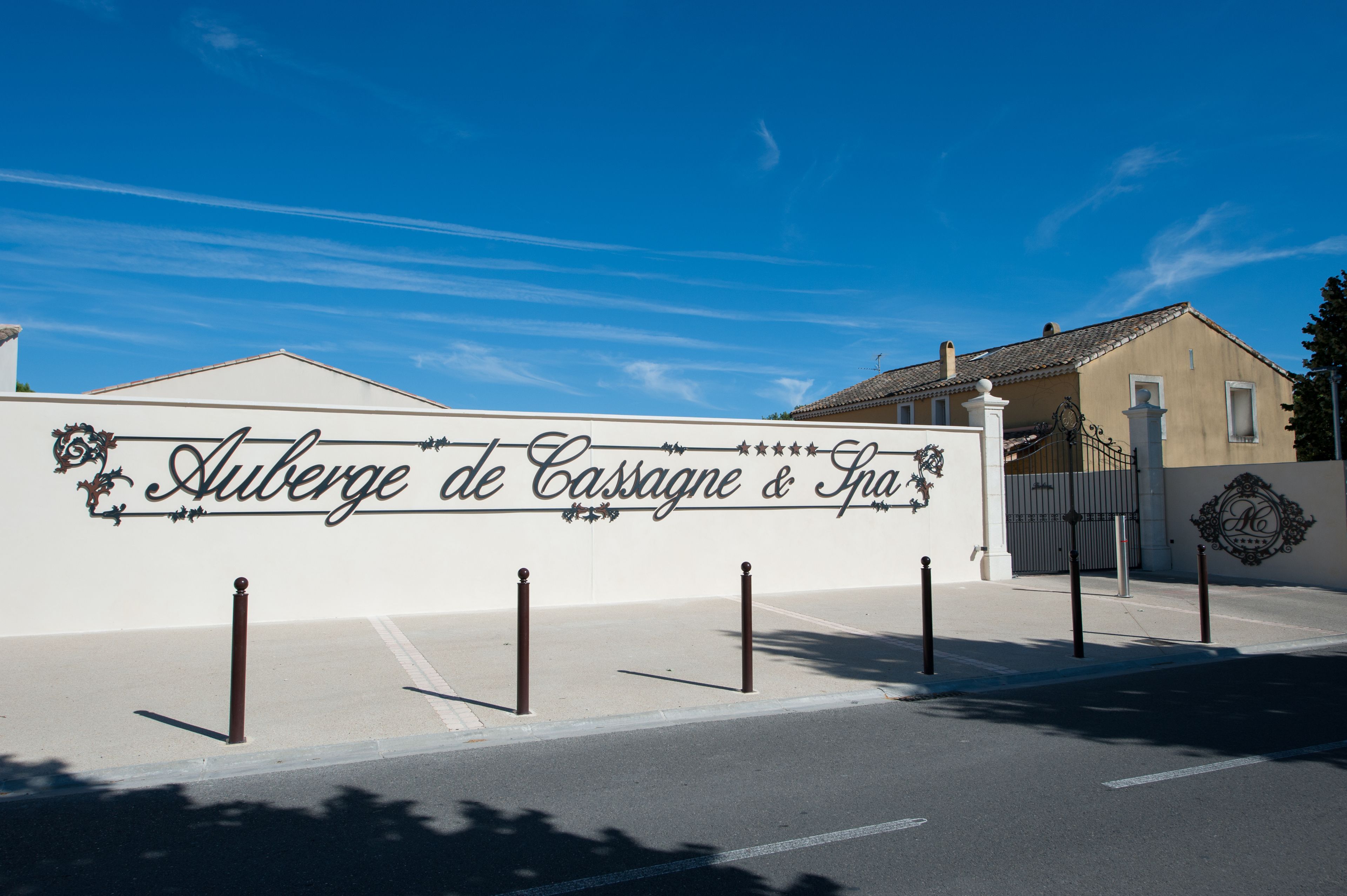 A sign for Auberge de Casseigne & Spa with a white wall and decorative lettering.
