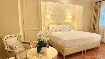 Een hotelkamer met een groot bed, een ronde tafel met een bloemenvaas en twee stoelen.