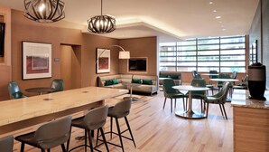 A modern hotel lobby with a long wooden reception desk, green upholstered seating, and large windows offering a view of the outdoors. - Residence Inn by Marriott Vancouver Downtown (Vancouver)