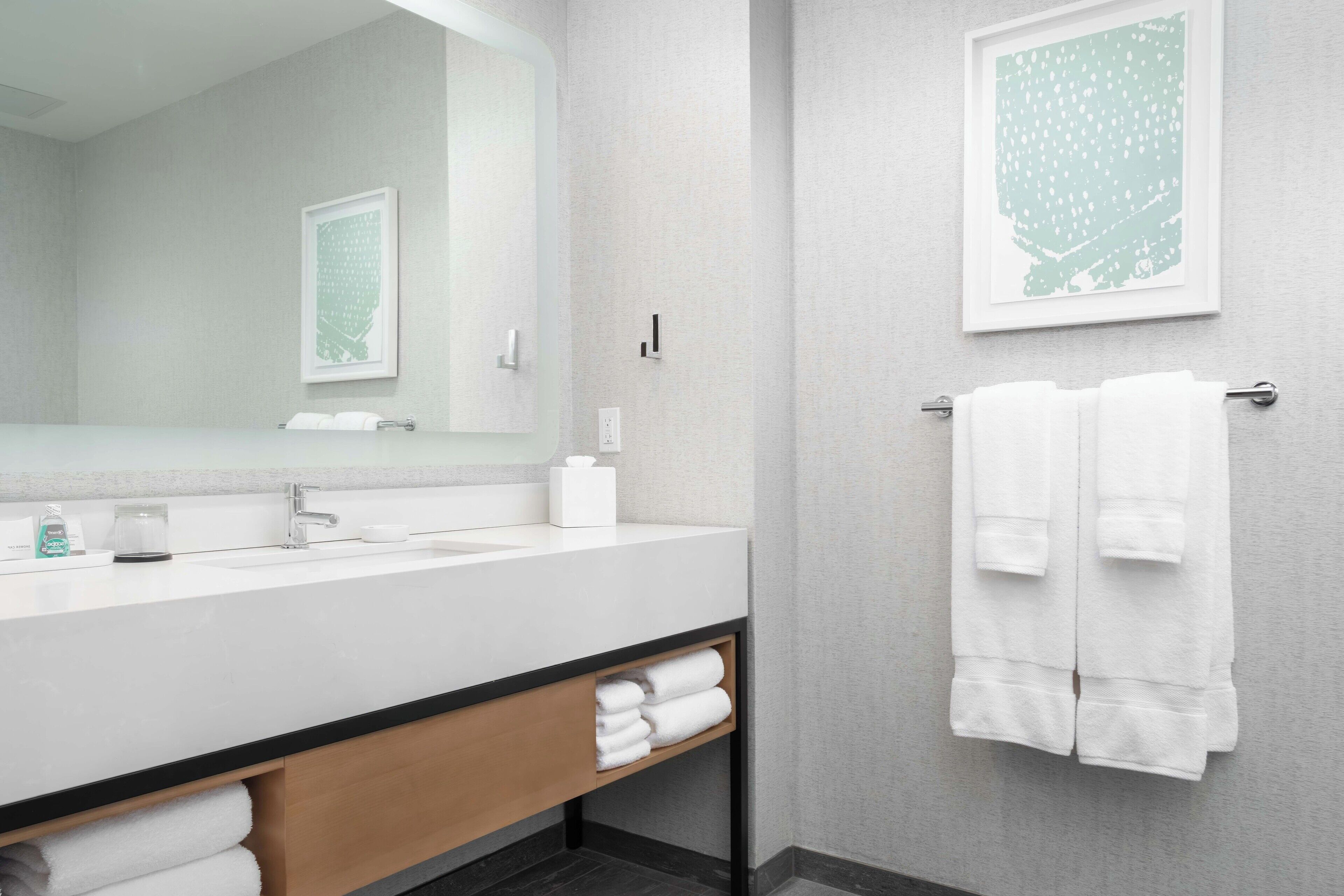 A modern bathroom with a white sink, mirror, and towel rack.