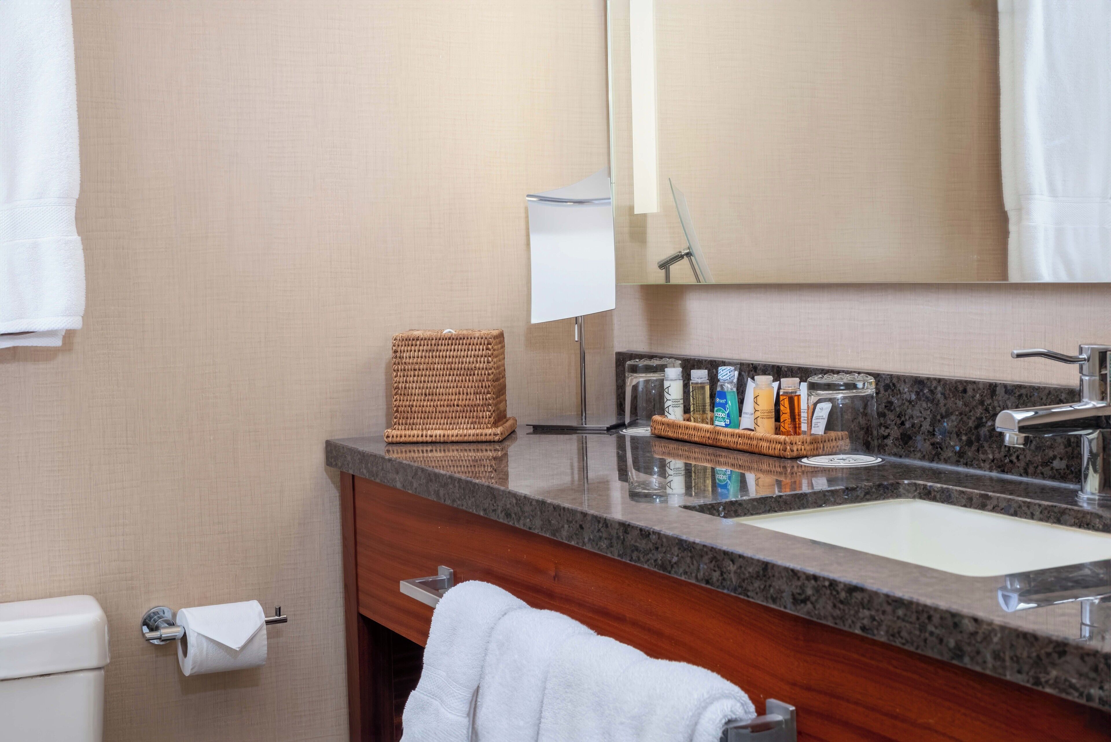 Un baño con lavabo, espejo, toallero y artículos de aseo.