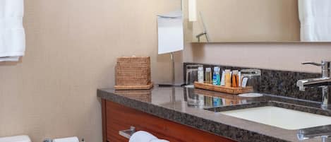 Un baño con lavabo, espejo, toallero y artículos de aseo.