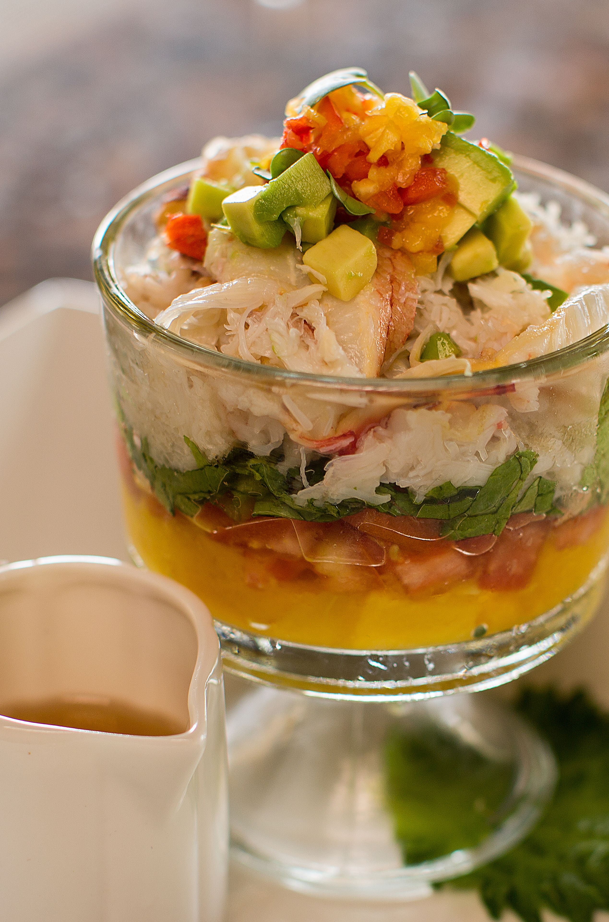 A layered seafood salad in a glass bowl.