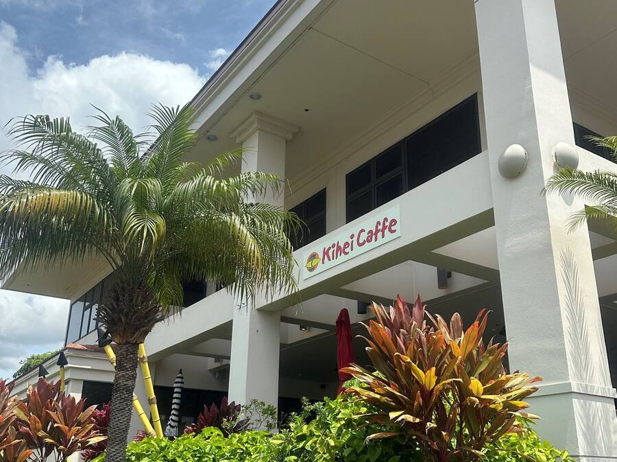 A building with a sign reading "Kihei Caffe" and a palm tree in front.
