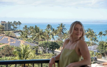 A balcony with a view of the ocean and palm trees.