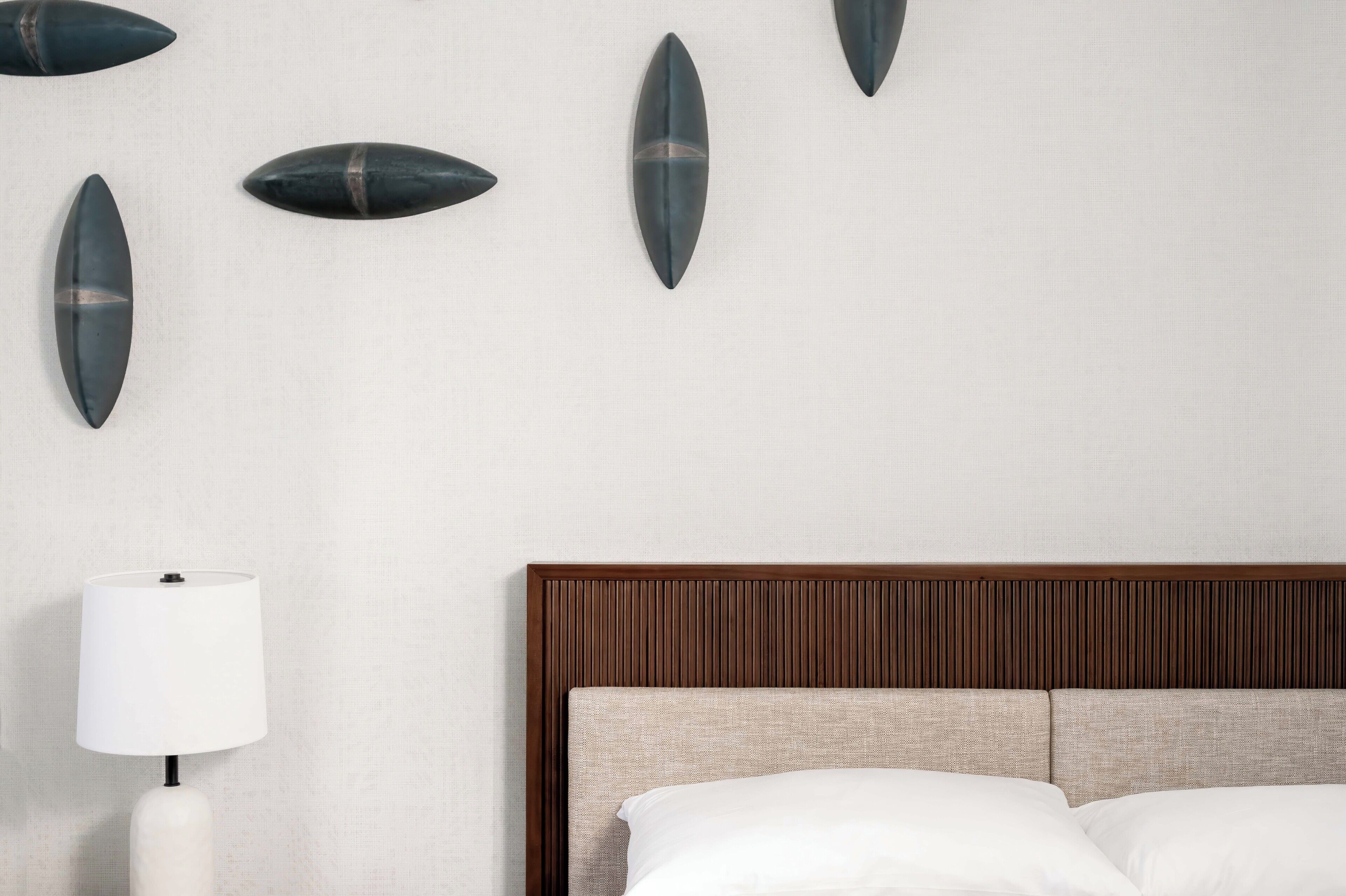 A hotel room with a bed, a bedside lamp, and wall-mounted decorative items.