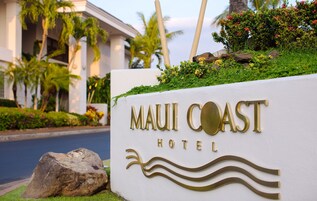 Skilt for Maui Coast Hotel med bølgemotiv og palmer i baggrunden.