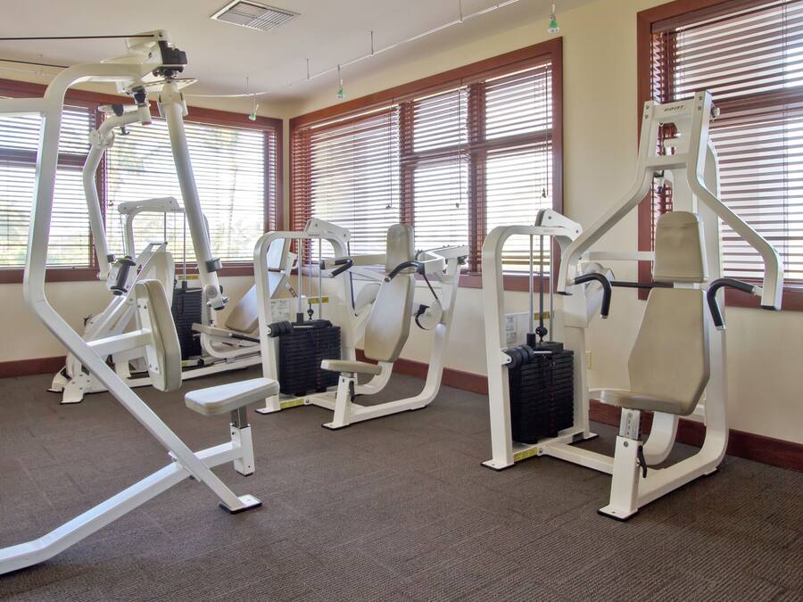 A gym with exercise equipment, large windows, and a carpeted floor.