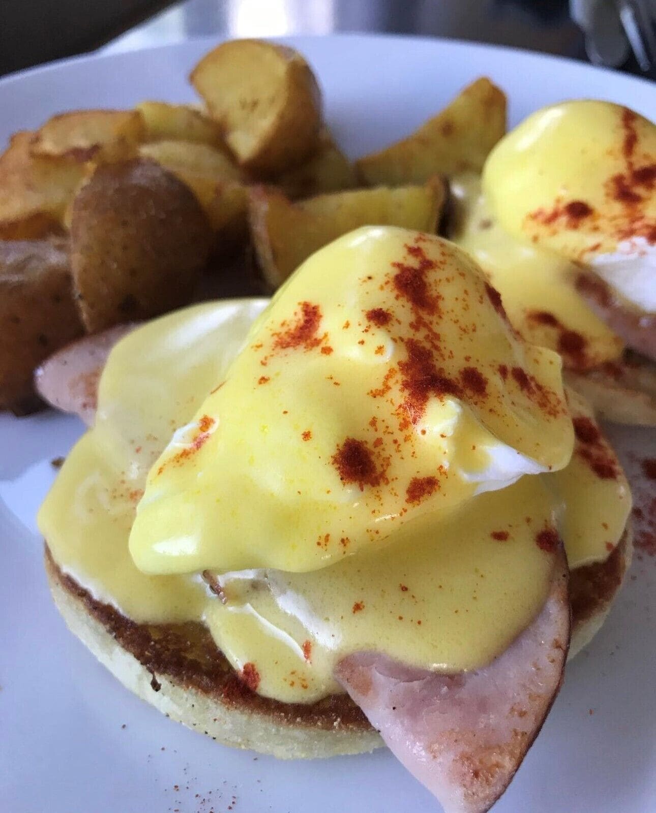 A plate with eggs benedict and hash browns.
