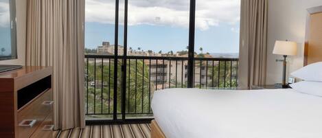 Une chambre d’hôtel avec une grande fenêtre, un lit, une télévision et un bureau.