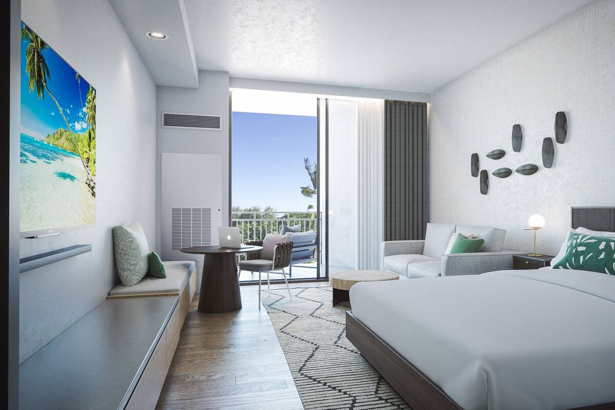 Una habitación de hotel moderna con una cama grande, un escritorio con una computadora portátil, un balcón con mobiliario exterior y un cuadro grande con una playa.