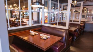 A restaurant interior with booths, tables, and hanging lights.