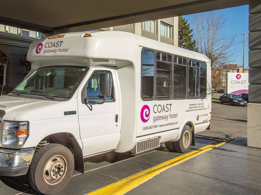 A white Coast Gateway Hotel branded bus parked at a hotel entrance.