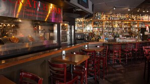 A bar area with a grill, bar counter, and seating.
