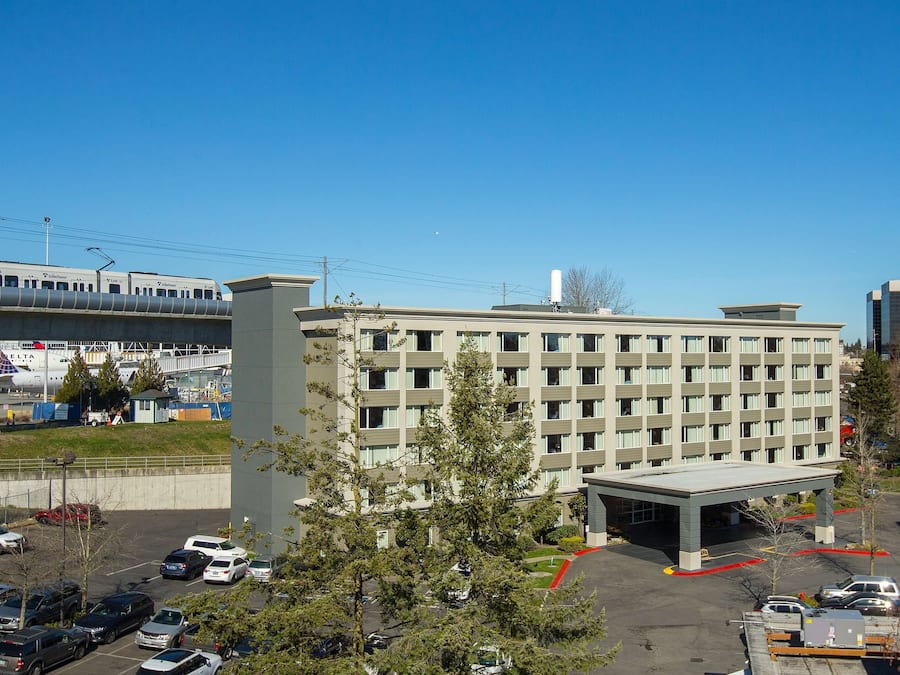 Et hotel med flere etager og en parkeringsplads foran.