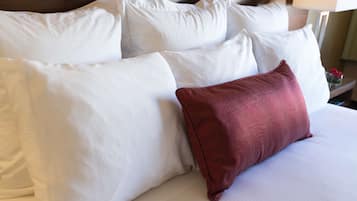 Una cama con muchos almohadones, incluyendo uno rojo llamativo.