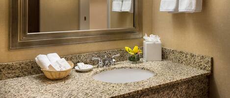 A bathroom with a granite countertop, a sink, a mirror, and a towel rack.