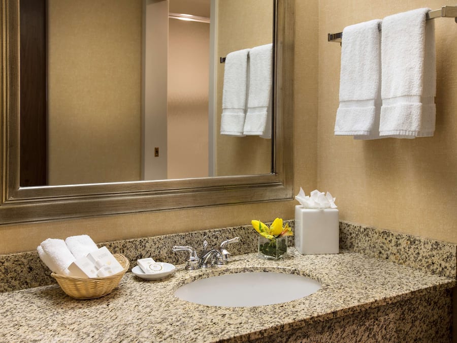 A bathroom with a granite countertop, a sink, a mirror, and a towel rack.