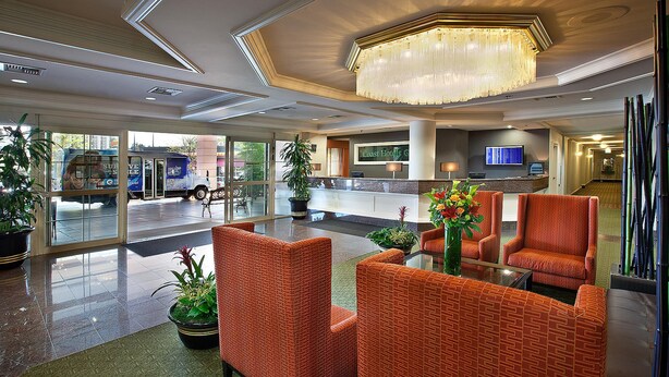 A hotel lobby with a reception desk, seating area, and a large chandelier.
