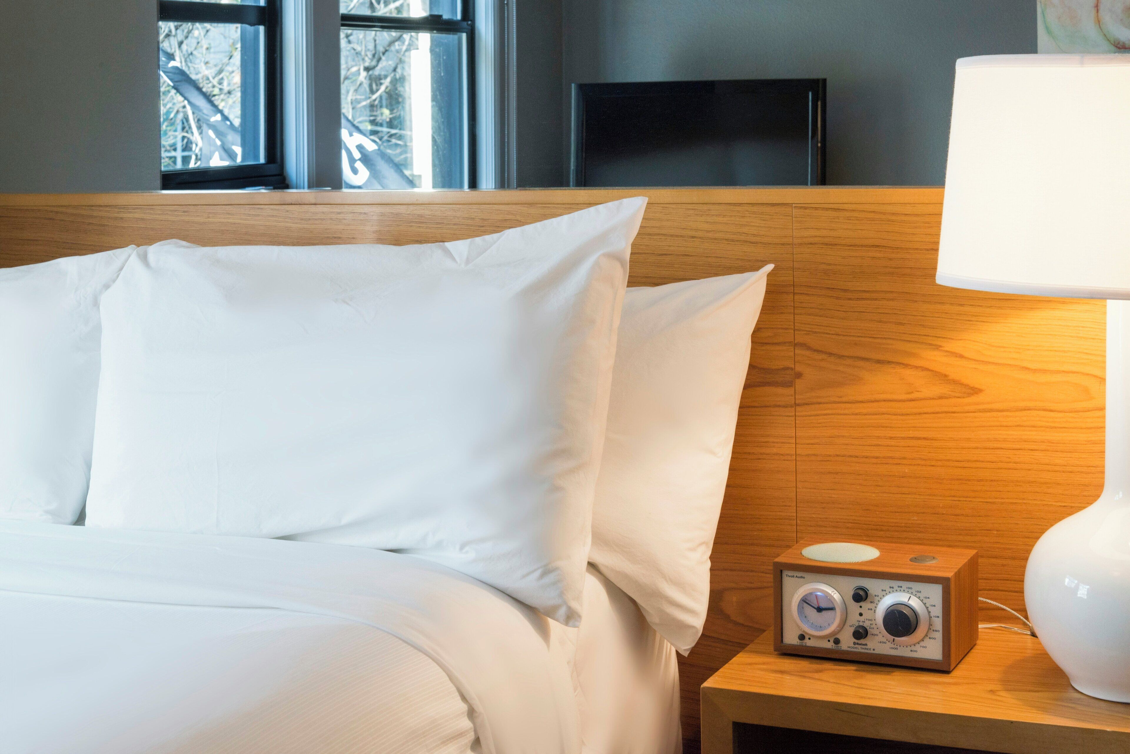 A neatly made bed with white linens in a hotel room.