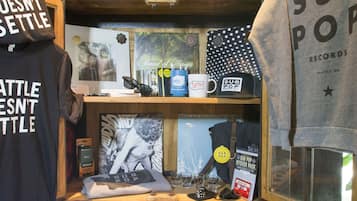 A display with various items including a 'Sub Pop' mug, a 'Sub Pop' sticker pack, and a 'Seattle Doesn't Settle' t-shirt.