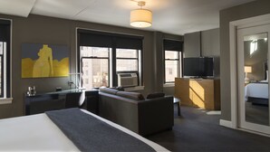 A modern hotel room with a large bed, a desk, a sofa, a TV, and a painting on the wall. - Hotel Max (Seattle)