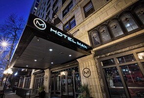 A hotel entrance with a prominent sign, large windows, and a covered entrance area.