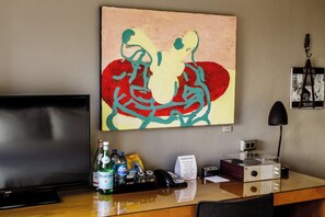 A hotel room with a flat-screen TV, a desk with a telephone, a coffee machine, and a wall-mounted artwork. - Hotel Max (Seattle)