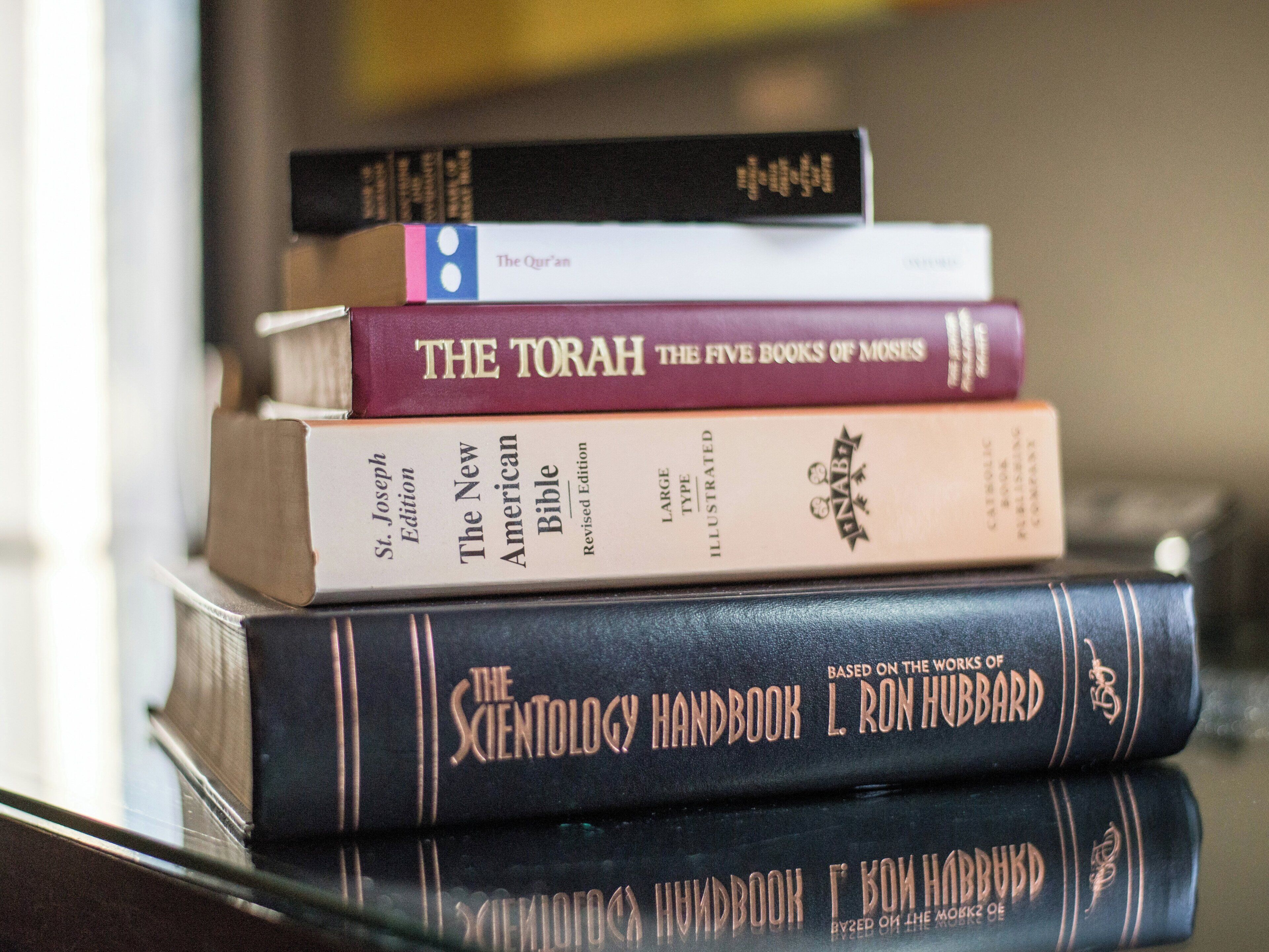 A stack of books including 'The Torah' and 'The Science of Theology Handbook' on a shelf.