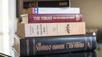 A stack of books including 'The Torah' and 'The Science of Theology Handbook' on a shelf.
