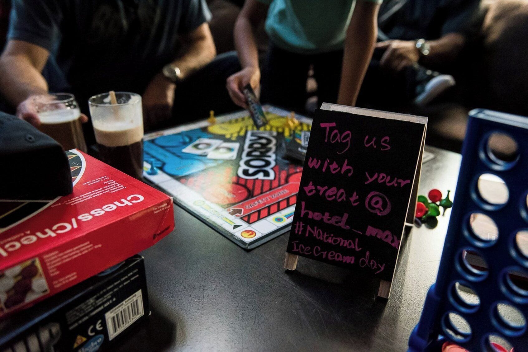 A table with a board game, a box of cereal, and a sign asking to tag with a treat.