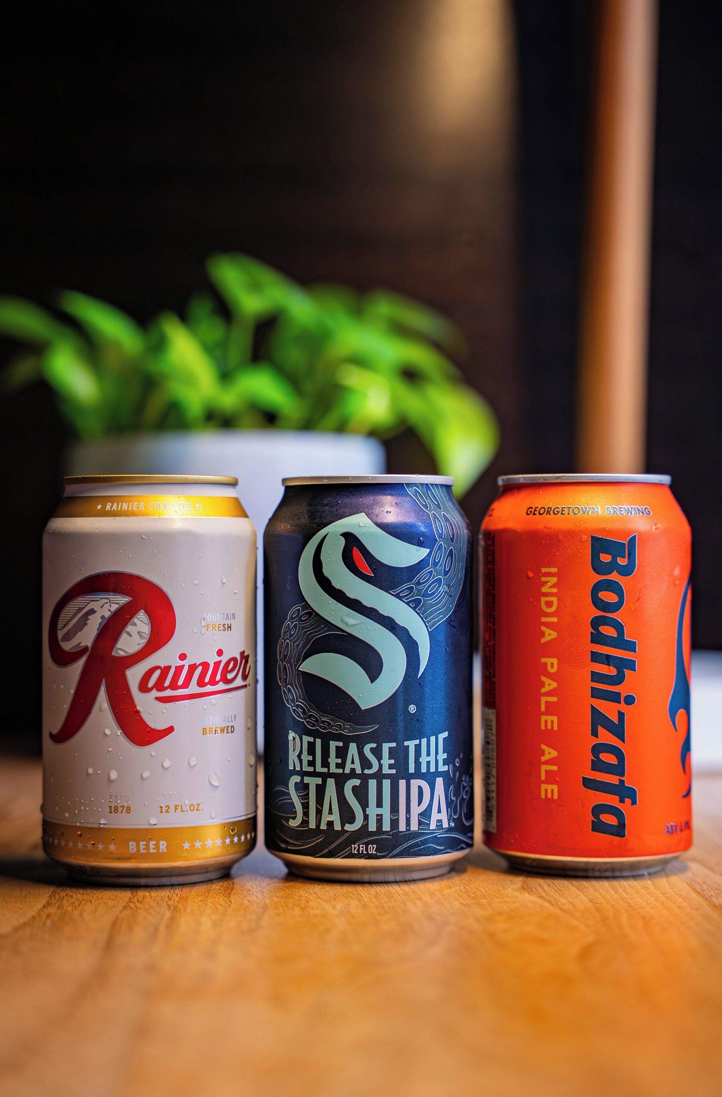 Three cans of beer on a wooden surface.