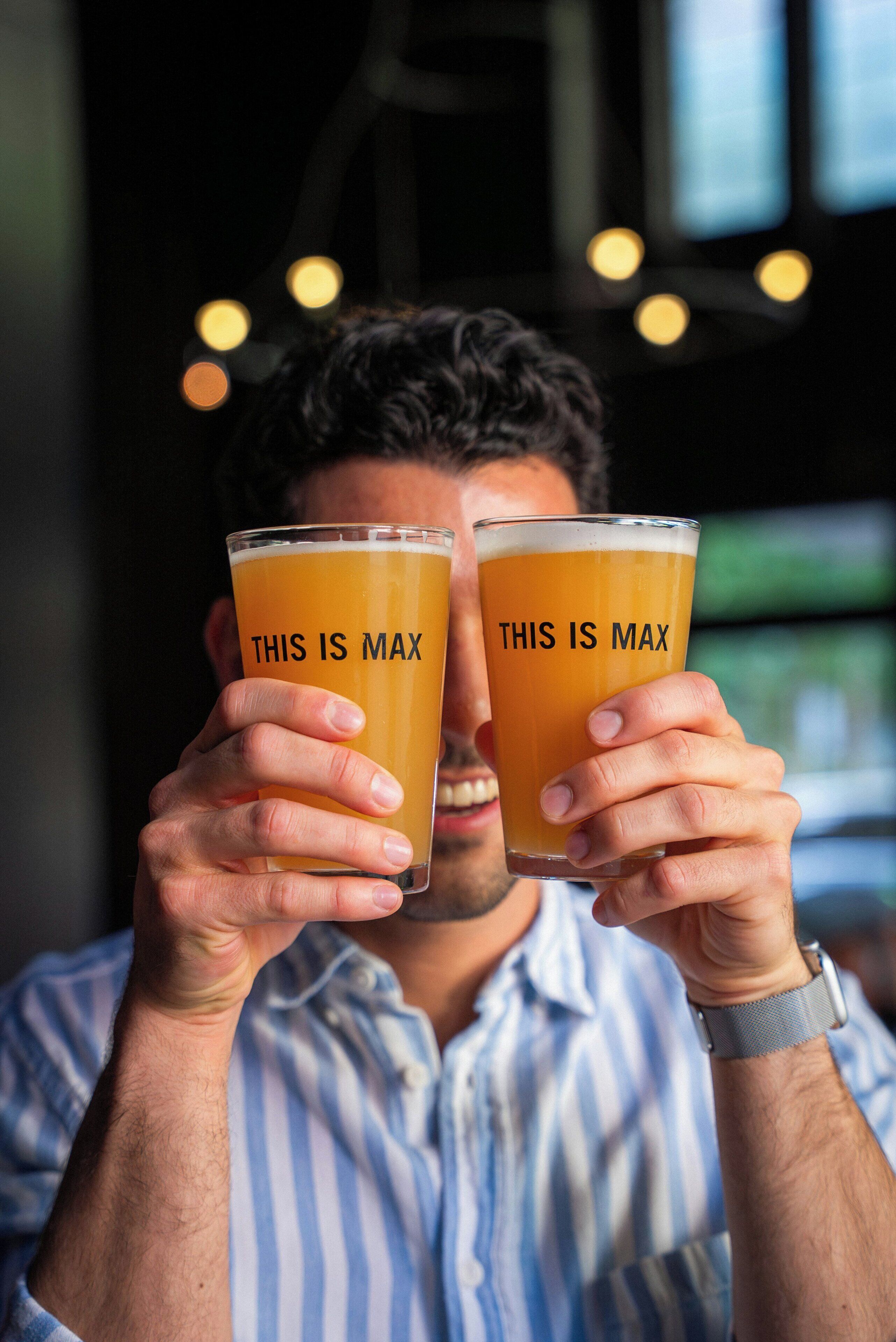 A person holding two glasses with the text 'THIS IS MAX' on them.