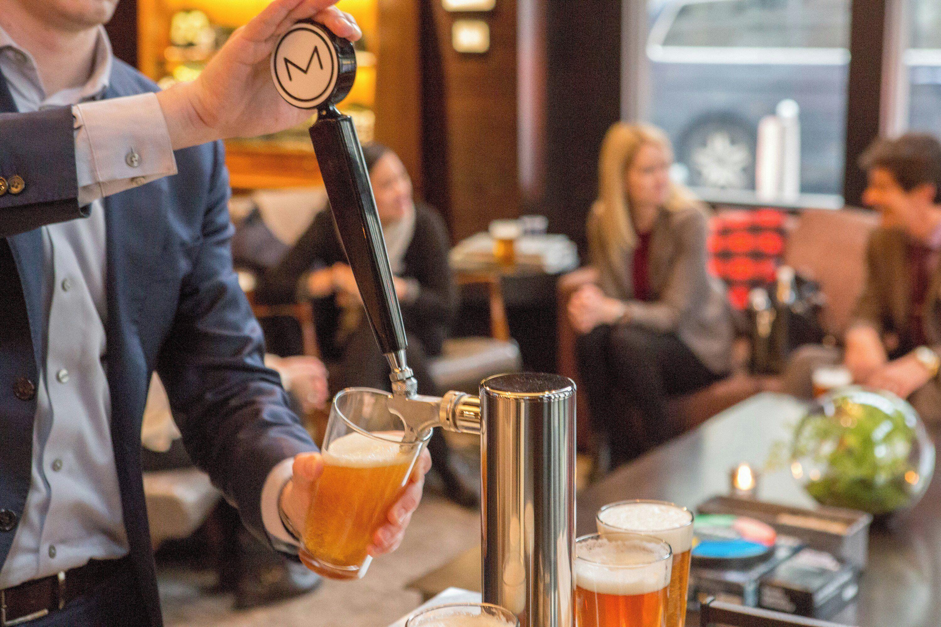 A bar setting with a person pouring beer into a glass.