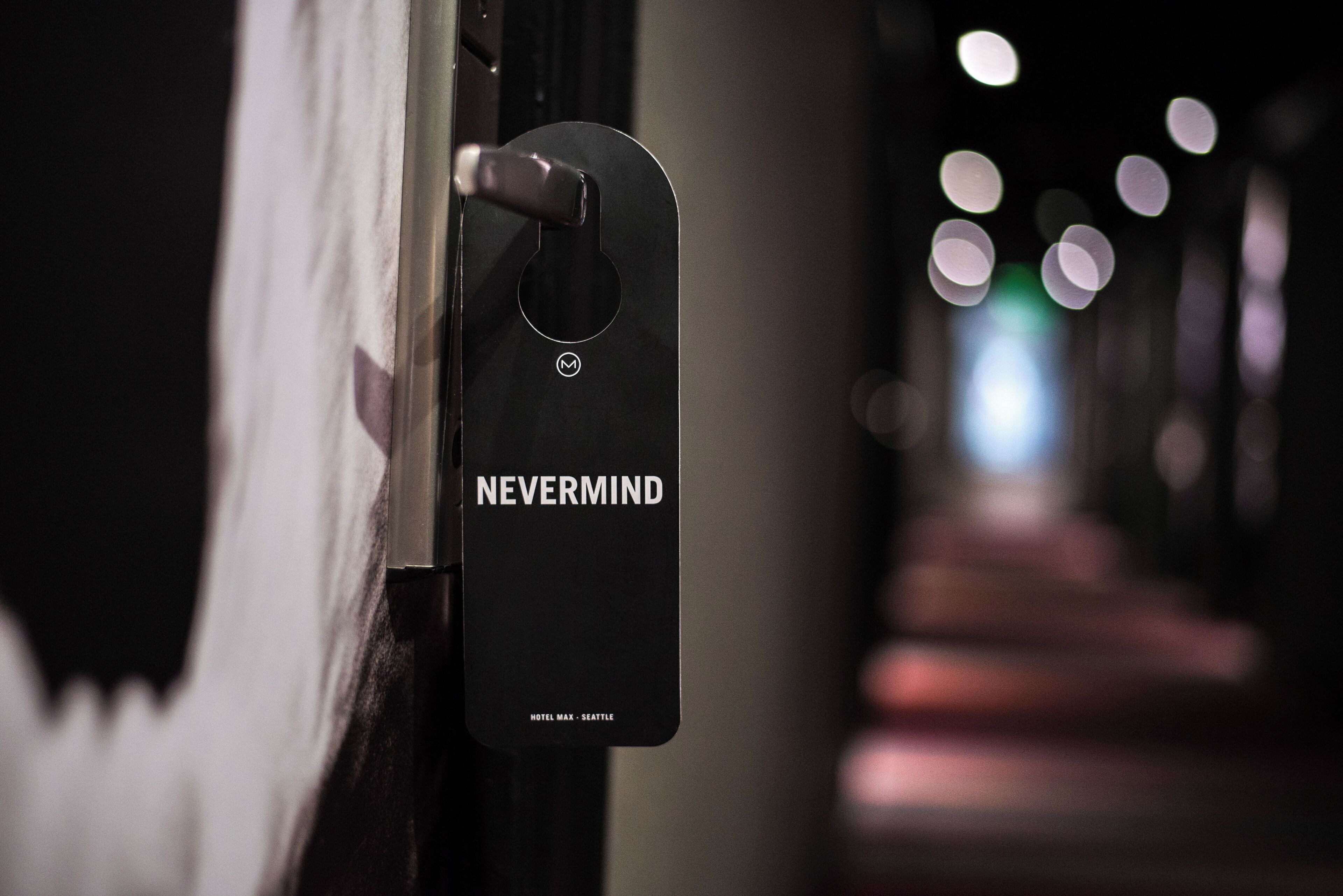Una llave de acceso negra con el texto "NEVERMIND" y "HOTEL MAX - SEATTLE", colgando de un picaporte.
