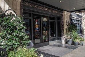 A hotel entrance with a black door, large windows, and potted plants.