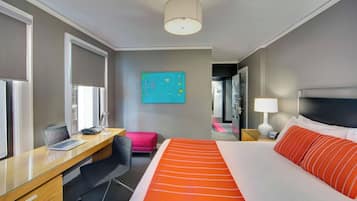 Une chambre d’hôtel avec un lit, un bureau, une chaise et un tableau au mur.