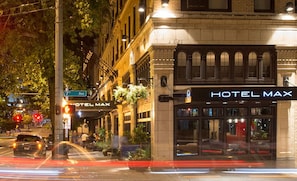 A building with a sign reading "HOTEL MAX" and a street sign for "7th Ave".