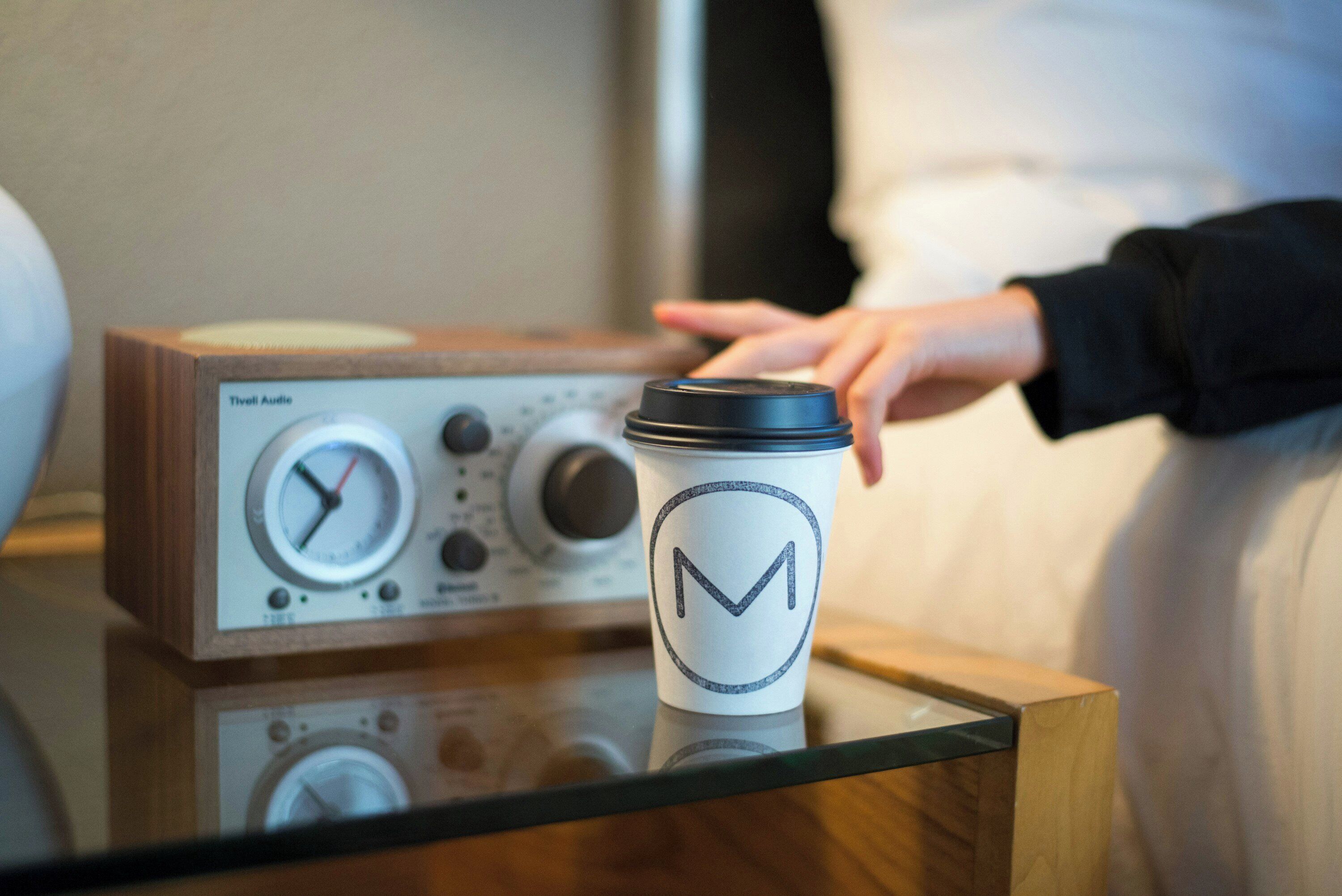 Eine Tasse mit einem Logo auf einem Tisch mit einem Radio.