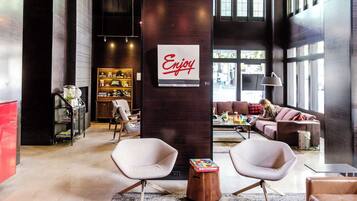 A modern interior with a central column featuring a 'Enjoy' sign, seating areas, and a visible storefront.