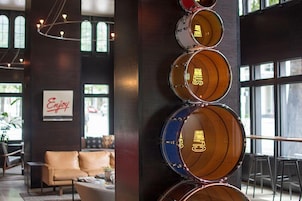 A modern interior with a drum set mounted on a wall, a leather sofa, and a sign that reads "Enjoy."