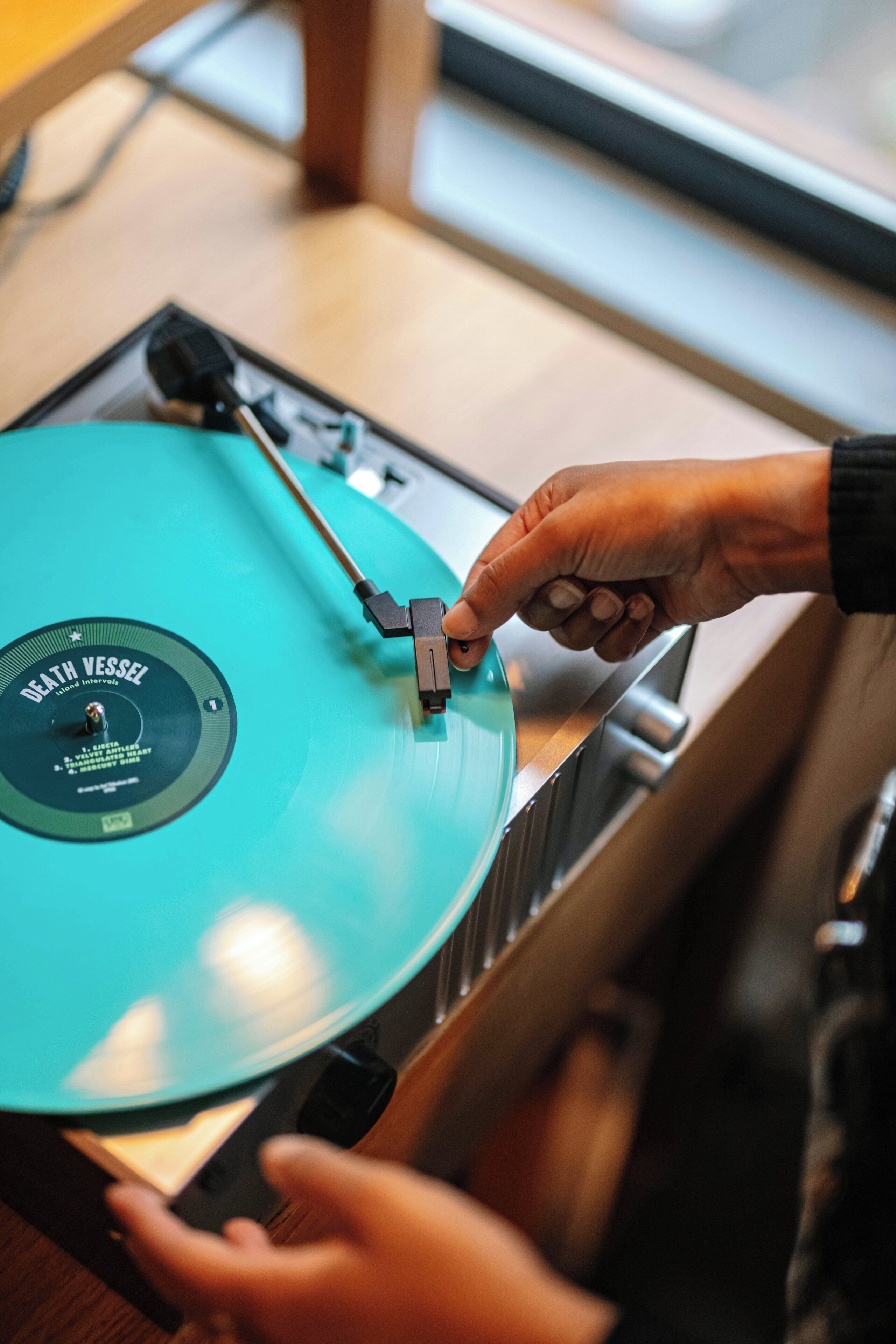 A person adjusting a turntable with a vinyl record.