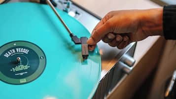 En person justerer en pladespiller med en vinylplade.