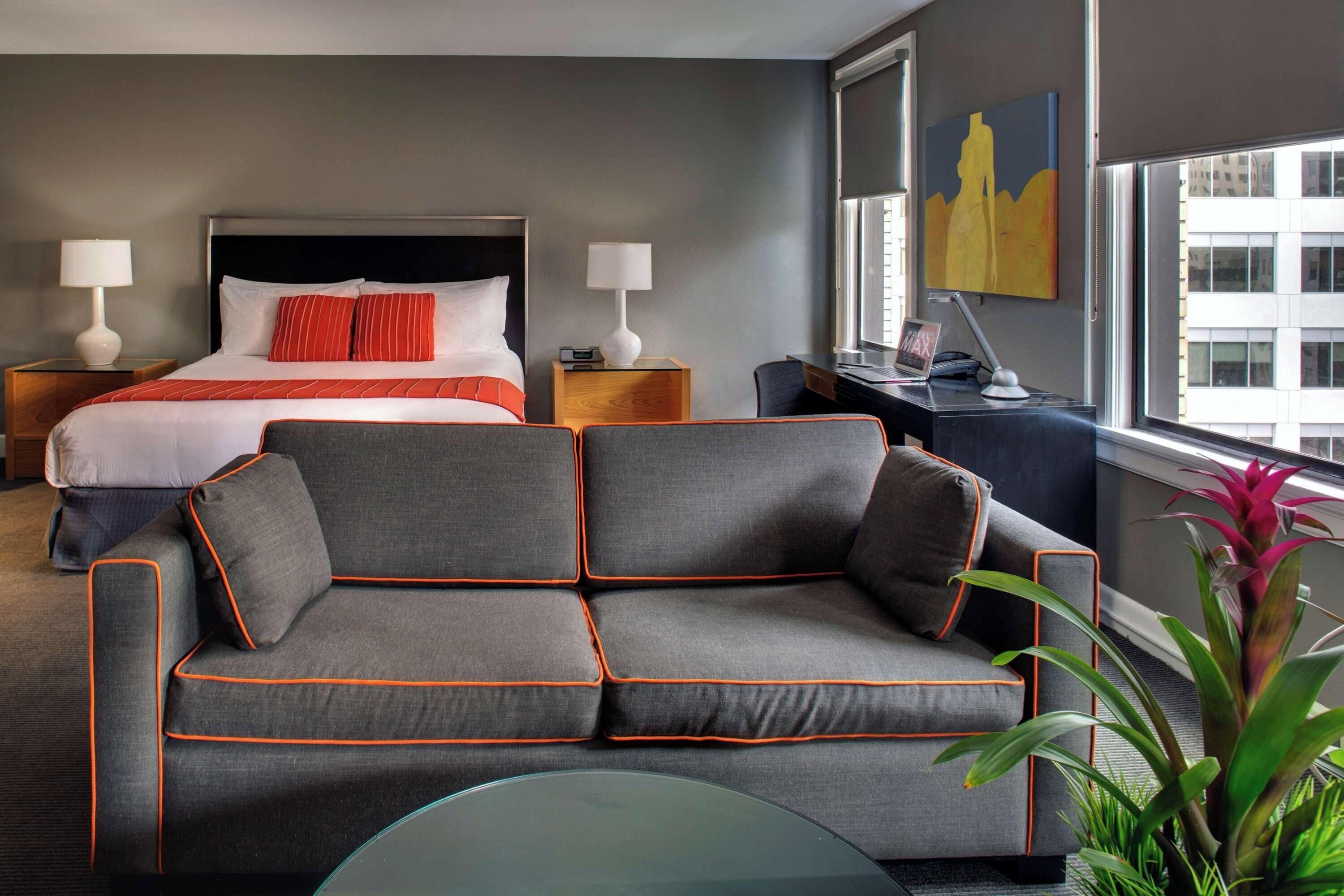 Habitación de hotel con cama, sofá, escritorio y ventana con vista a la ciudad.