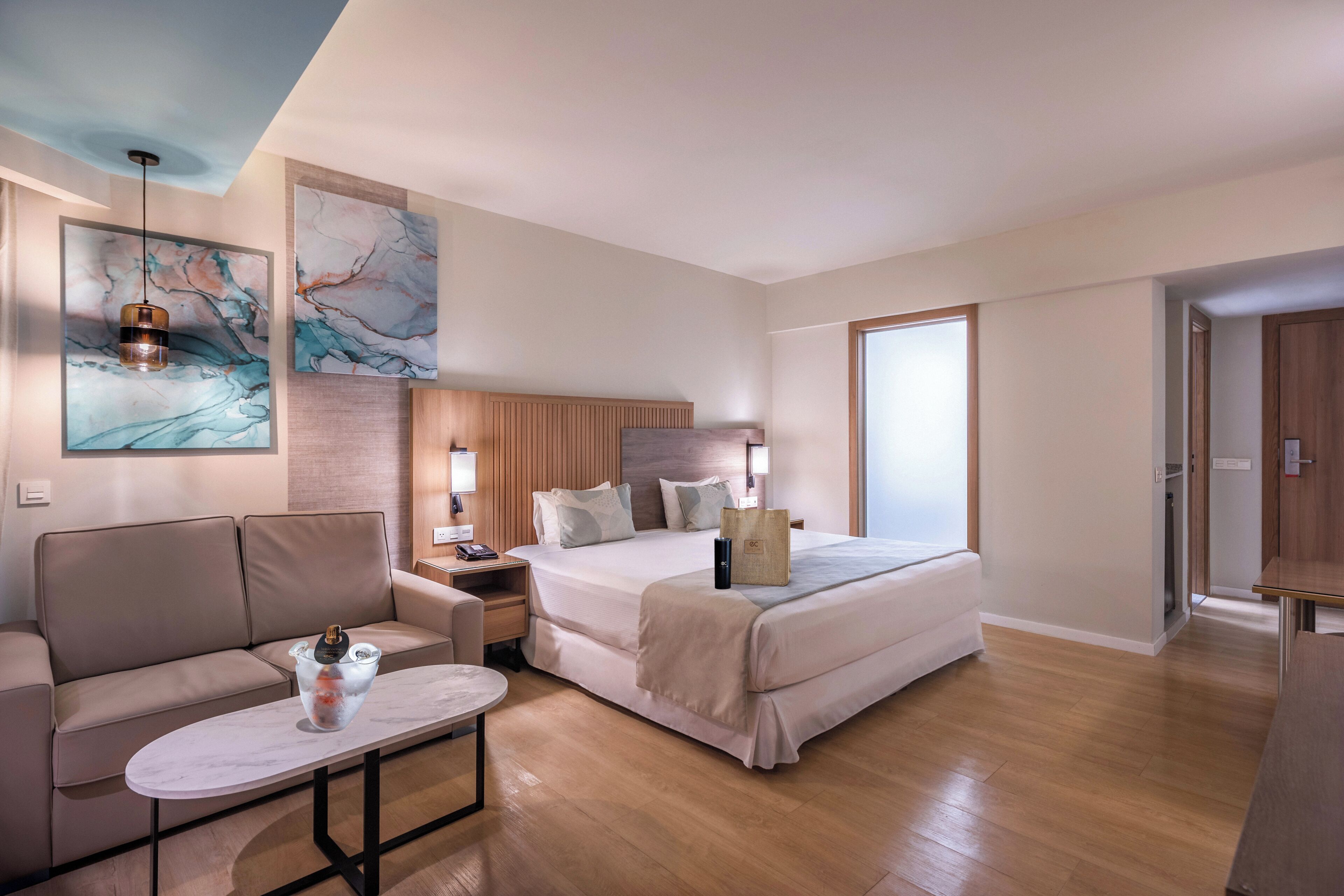 Una habitación de hotel moderna con una cama, un sofá, una mesita de noche y una mesa de centro.