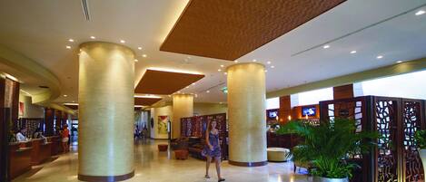 A spacious lobby with large columns, a reception desk, and a seating area.